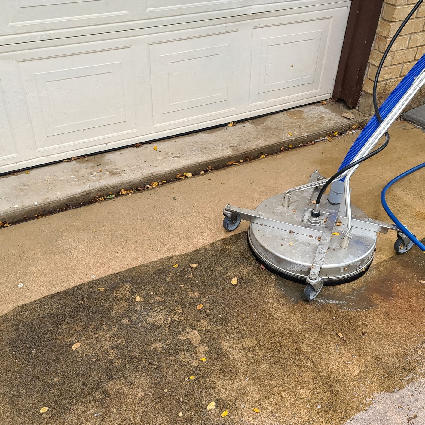 Commercial rotary surface cleaner washing a concrete driveway